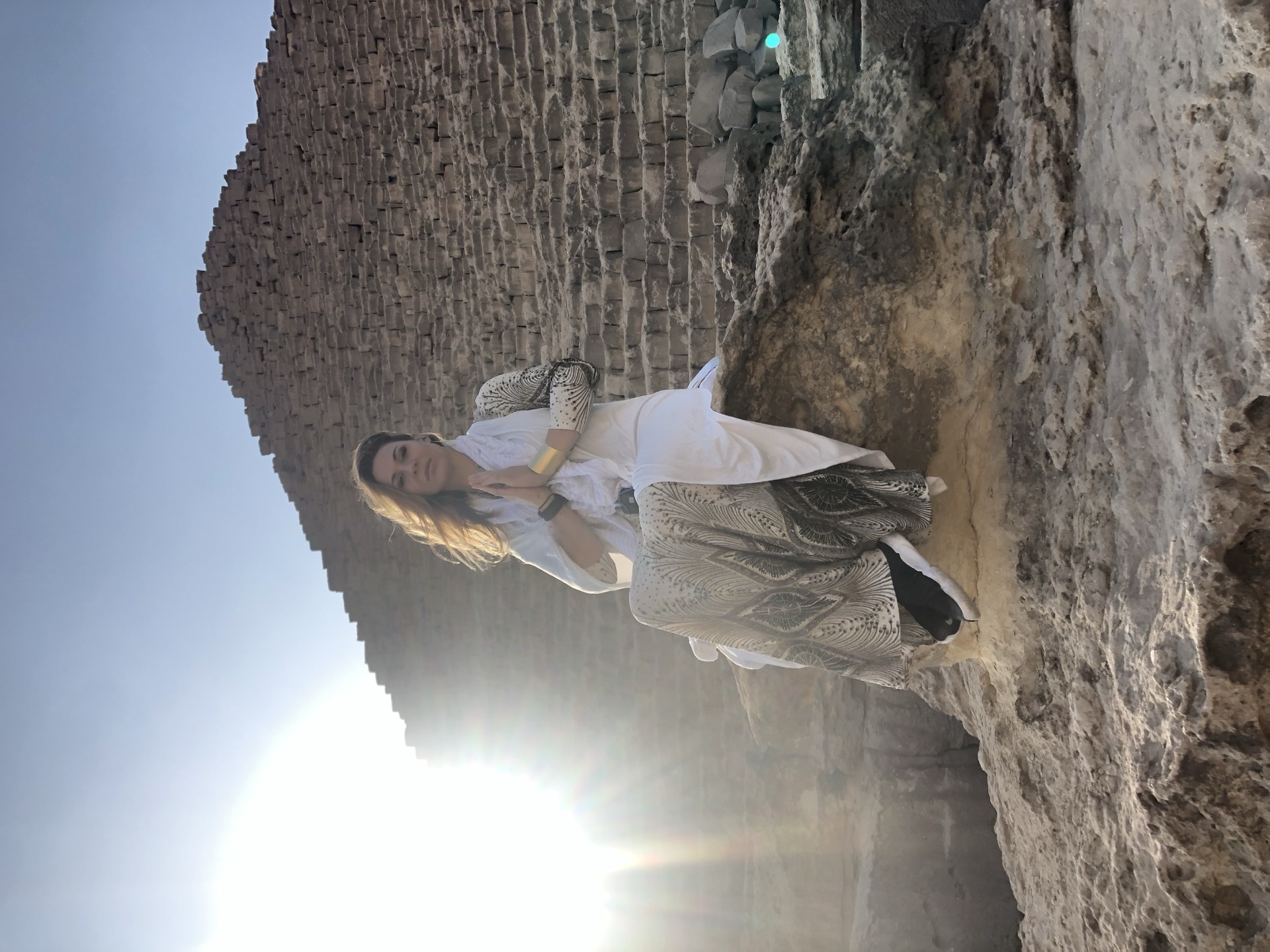 A woman seated in reflection in front of a stone pyramid